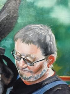 Painting of a man with glasses and a beard, wearing a dark shirt. His eyes are closed, and he appears contemplative. The background is a blurred mix of greens.