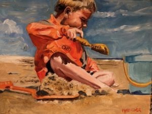 A child with light hair sits on a sandy beach, wearing an orange shirt. They are digging with a yellow shovel, a blue bucket nearby. The sky is bright and clear, suggesting a sunny day at this seaside marsh.