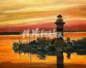 The painting Harbour Town Sunset captures a sunset with warm hues of orange, red, and yellow reflecting off the calm sea. Silhouetted trees and boats near the lighthouse enhance this serene scene.