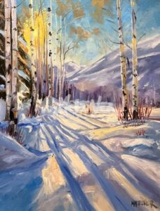 Aspen Glow features a snowy forest with sunlight streaming through tall birch trees, their long shadows on the snow. Majestic mountains and a clear blue sky complete this serene winter landscape.